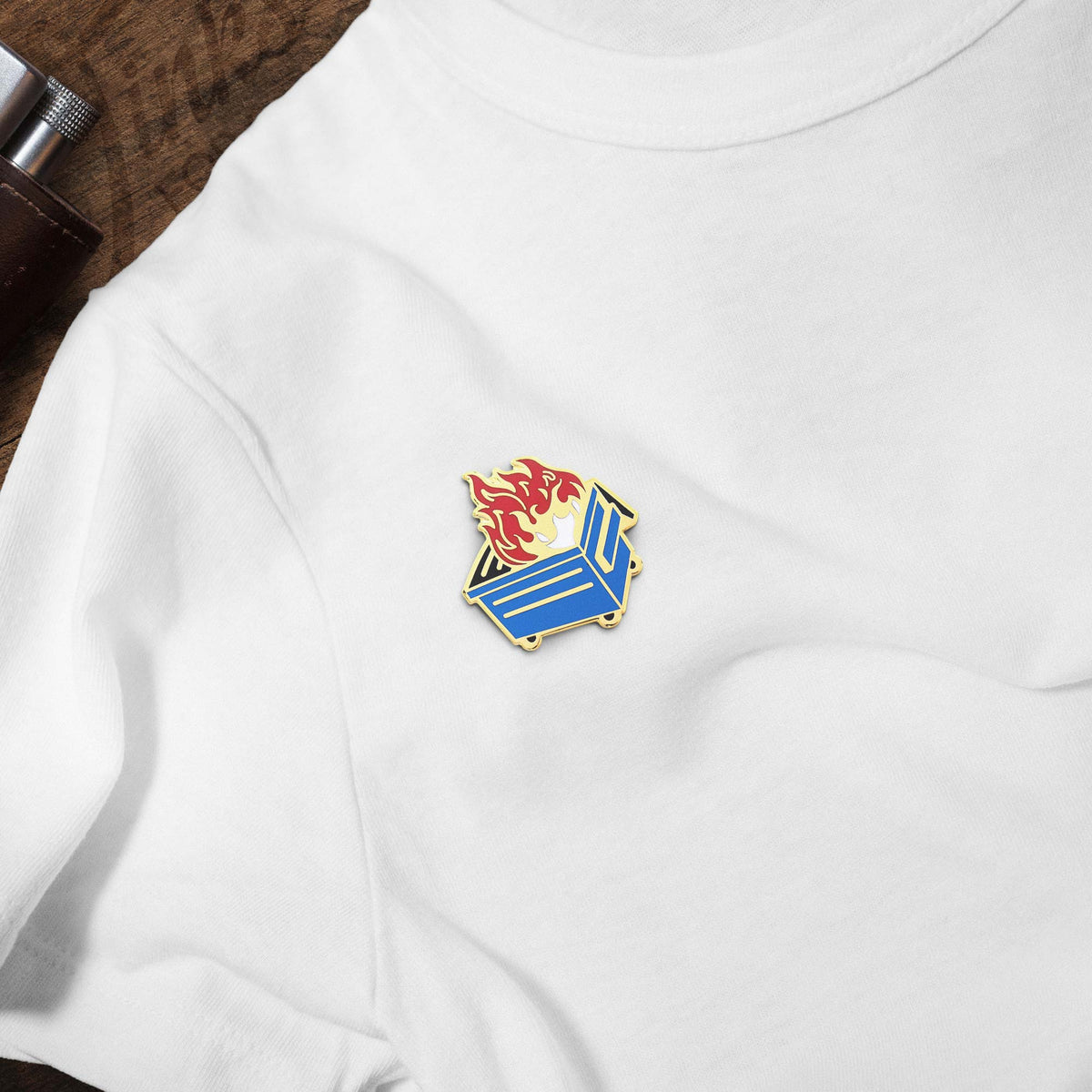 Blue Dumpster Fire hard enamel pin on white t-shirt