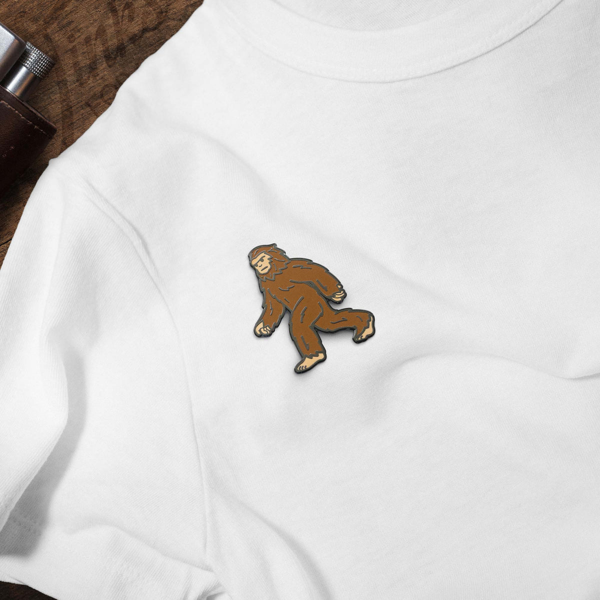 Bigfoot Sasquatch hard enamel pin on white t-shirt