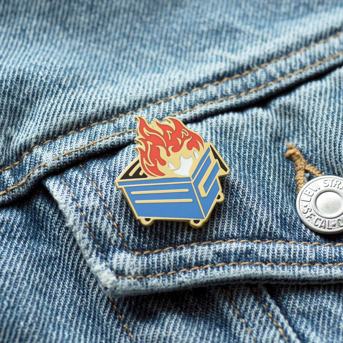 Blue Dumpster Fire hard enamel pin on denim jacket