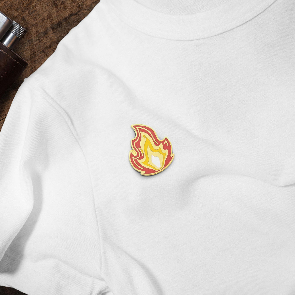 It's Fire hard enamel pin on white t-shirt